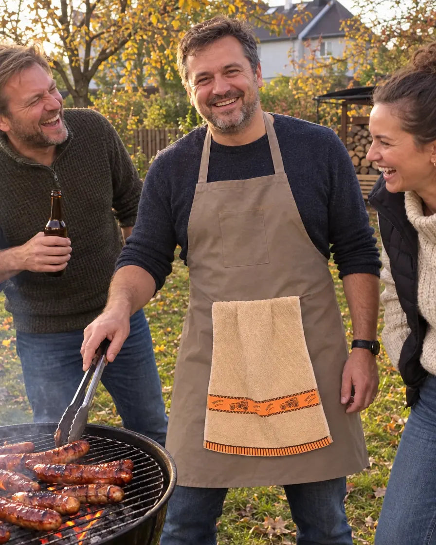 Mężczyzna w fartuchu z ręcznikiem przy grillu, znajomi się śmieją